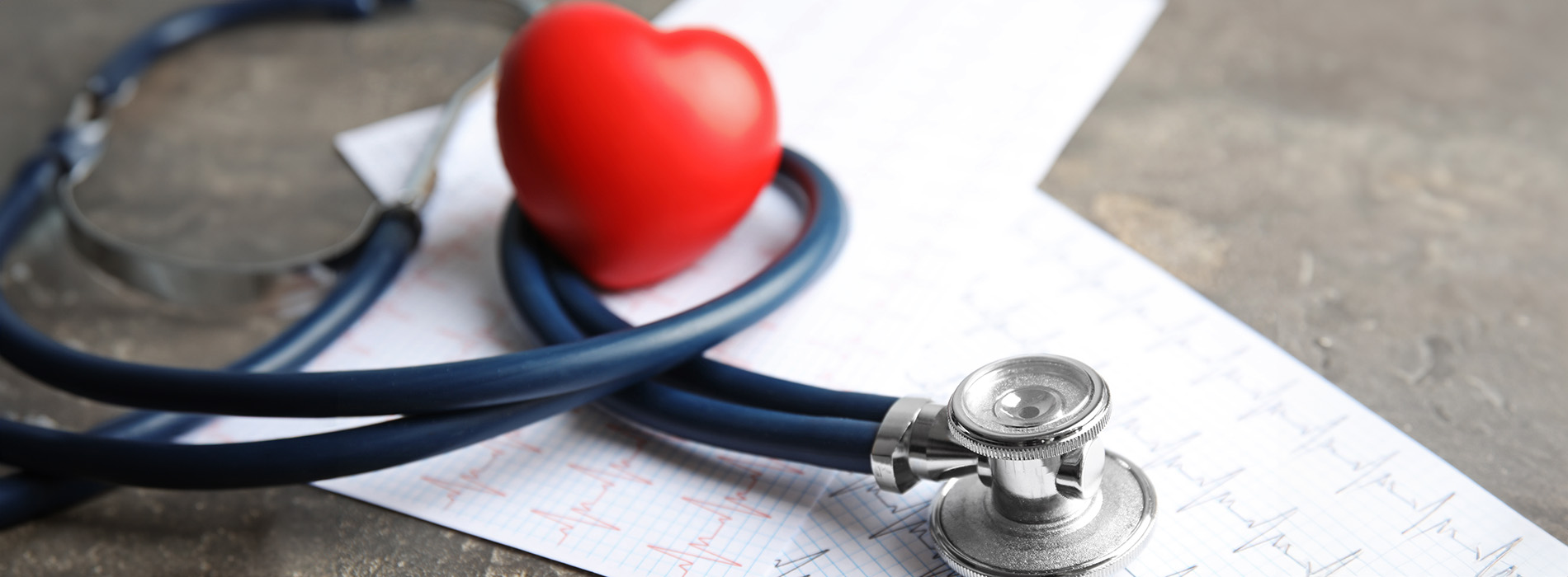 The image features a stethoscope with a heart-shaped pendant placed on top of a medical chart, accompanied by a red pill bottle labeled heart with a white cross inside.