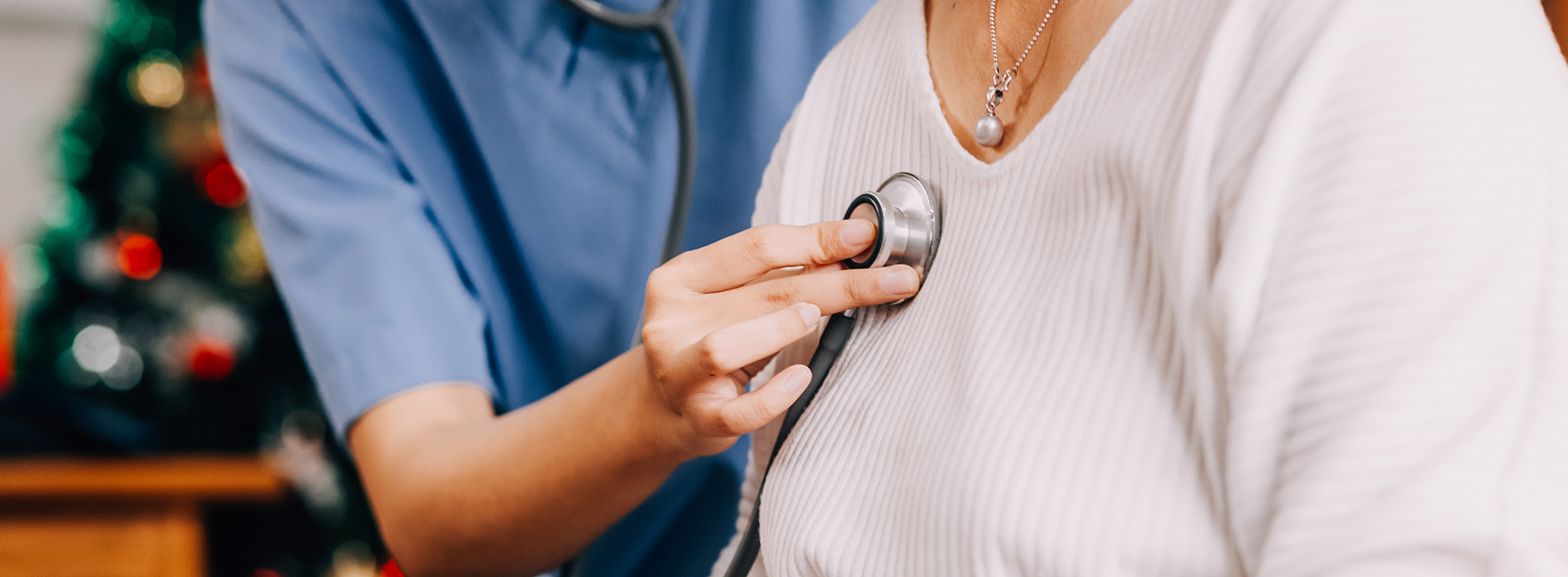 A medical professional, possibly a nurse, using a stethoscope on an elderly person s chest.