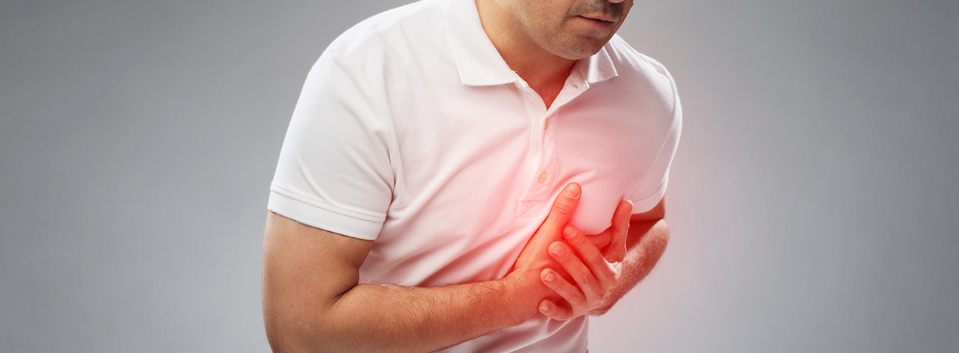 The image shows a man wearing a white shirt with his hand on his chest, appearing to be in a state of distress or discomfort.