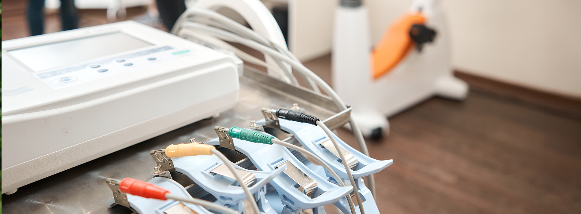 The image shows a table with various medical equipment on it, including a machine with a screen displaying graphs and a small robotic arm, suggesting a setting related to healthcare technology.